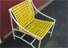 Tropitone patio chair with yellow vinyl strap seat.